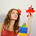 Portrait of having fun playing with toy airplane beautiful funny young lady in polka dot dress looking up over white