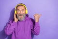 Portrait of healthy pensioner man purple hoodie touch headphones directing empty space sale discount isolated on violet