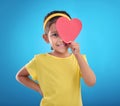 Portrait, heart cut out and girl with smile, joyful and cheerful against blue studio background. Face, female kid and