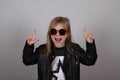 Portrait of a heavy metal little girl with sunglasses. Cute little girl making a rock-n-roll sign. Royalty Free Stock Photo