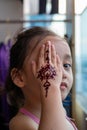 Portrait of Henna ornaments on little girl`s hand covering face Royalty Free Stock Photo