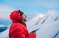 Portrait of high altitude mountaineer dressed red warm dawn jacket holding metal mug of hot tea thinking and enjoying fresh