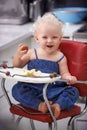Portrait, high chair and kid with apple, healthy diet and nutrition for breakfast. Hungry, baby and toddler eating fruit Royalty Free Stock Photo