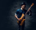 Portrait of the hipster bass player dressed in cylinder hat. Royalty Free Stock Photo