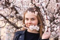 Portrait of hipster girl standing in spring blossom flowers garden and look at camera. Beautiful happy young woman enjoying smell Royalty Free Stock Photo