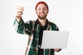 Portrait of hipster man holding silver laptop and credit card, while standing isolated over white background Royalty Free Stock Photo