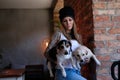 Portrait of a hipster tattoed girl dressed in white t-shirt and hat holds her little dogs in room with loft interior. Royalty Free Stock Photo