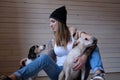 Portrait of a hipster tattoed girl playing with her little dogs while sitting on a wooden floor. Royalty Free Stock Photo