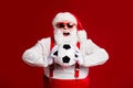 Portrait of his he attractive cheerful cheery glad fat white-haired Santa holding in hands throwing soccer ball hobby