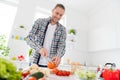 Portrait of his he nice attractive cheerful cheery guy making cooking tasty yummy useful lunch chopping tomato culinary