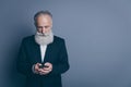 Portrait of his he nice attractive chic classy focused concentrated gray-haired man wearing tux using modern device