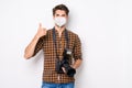 Portrait of his he nice attractive healthy guy showing thumbup holding in hands camera wearing reusable safety mask mers