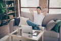 Portrait of his he nice attractive muscular cheerful cheery guy sitting on divan resting working remotely part-time at Royalty Free Stock Photo