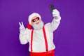 Portrait of his he nice funny cheerful cheery bearded Santa taking making selfie showing v-sign travel trip blogging Royalty Free Stock Photo