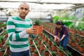 Portrait of a hispanic farmer holding an ornamental shrub.