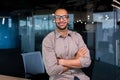 Portrait of hispanic successful businessman, successful man in shirt looking at camera with crossed arms, worker inside