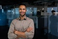 Portrait of hispanic successful businessman, successful man in shirt looking at camera with crossed arms, worker inside