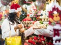 Hispanic woman in Santa hat choosing decorations at street Christmas fair Royalty Free Stock Photo
