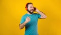 Portrait of hispanic young man with headphones, dancing and listening music on yellow background in Mexico Latin America