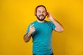 Portrait of hispanic young man with headphones, dancing and listening music on yellow background in Mexico Latin America