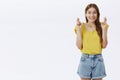 Portrait of hopeful charming european female adult with beautiful hair in yellow t-shirt crossing fingers for good luck