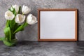 Portrait horizontal white picture frame mockup on vintage dark table with tulips jug vase grey concrete wall background. Royalty Free Stock Photo