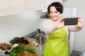 Portrait of housewife in apron making selfie in domestic kitchen Royalty Free Stock Photo