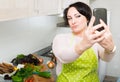 Portrait of housewife in apron making selfie in domestic kitchen Royalty Free Stock Photo