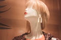 Portrait of human female blonde mannequin in shop window. White doll with red lips and white earrings in jacket Royalty Free Stock Photo