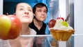 Portrait of hungry man and woman looking for something to eat in fridge at night Royalty Free Stock Photo