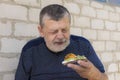 hungry Ukrainian senior taking in hand and ready to eat vegan sandwich with cucumber, yellow tomato and guacamole Royalty Free Stock Photo