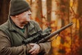 Portrait of hunter or ranger with gun or rifle in the forest looking out or hunting of some venison, hunting period Royalty Free Stock Photo