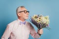 Portrait of husband aged guy with wild flowers bunch prepare for date ob blue background Royalty Free Stock Photo