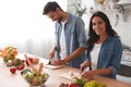 Portrait of husband cutting vegetables with wife smiling at the camera