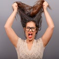 Portrait of a hysterical woman pulling hair out against gray background