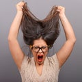 Portrait of a hysterical woman pulling hair out against gray background