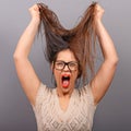 Portrait of a hysterical woman pulling hair out against gray background