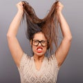 Portrait of a hysterical woman pulling hair out against gray background