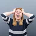 Portrait of a hysterical woman pulling hair out against gray background