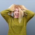 Portrait of a hysterical woman pulling hair out against gray background