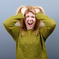 Portrait of a hysterical woman pulling hair out against gray background