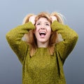 Portrait of a hysterical woman pulling hair out against gray background