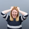 Portrait of a hysterical woman pulling hair out against gray background