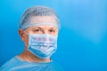 Portrait of ill man in medical unifrom and protective mask with stop text at blue background. Respiratory protection. Royalty Free Stock Photo