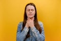 Portrait of ill sad young woman standing touching neck and frowning from pain, suffering sore throat, flu symptom, wearing denim Royalty Free Stock Photo