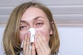 Portrait of ill sick woman sneezing, coughing, blowing her nose in handkerchief on light background, close-up. Concept diseases of Royalty Free Stock Photo