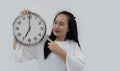 Portrait image of beautiful Asian woman doing countdown holding big clock over isolated white background Royalty Free Stock Photo