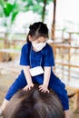 Portrait image child 5 year old. Cute Asian girl is riding on back of black buffalo. Children get close to farm animals.