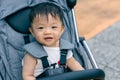 Happy and cute Asian Chinese baby boy sitting on stroller at park during evening Royalty Free Stock Photo