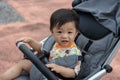 Happy and cute Asian Chinese baby boy sitting on stroller at park during evening Royalty Free Stock Photo